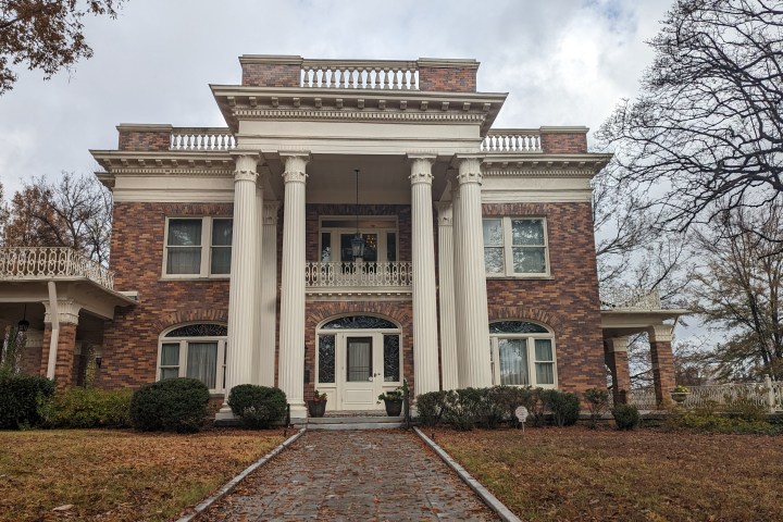 a large brick building with grass in front of a house