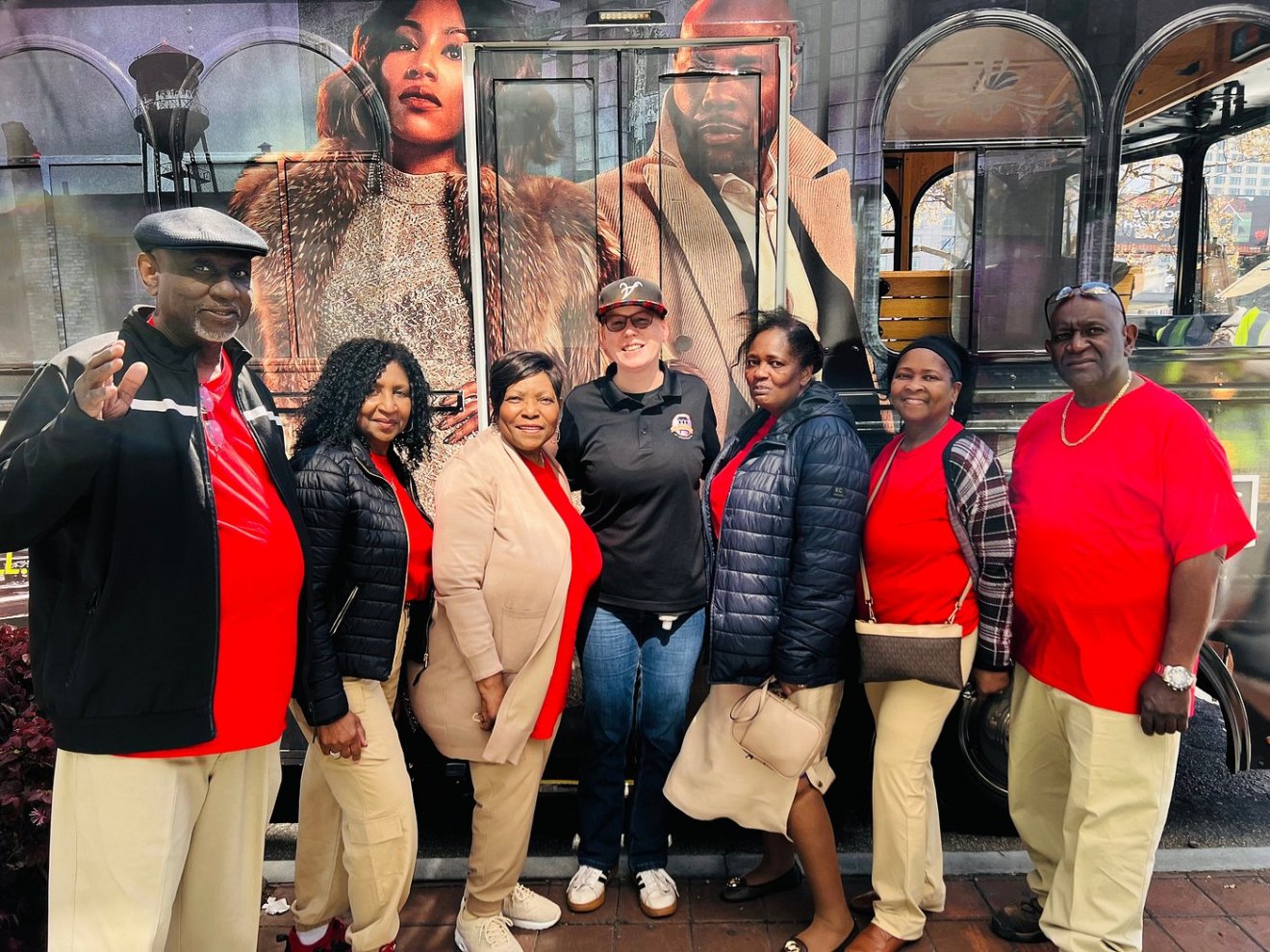 Group of people in front of a bus with celebrity images, smiling and posing for a photo.