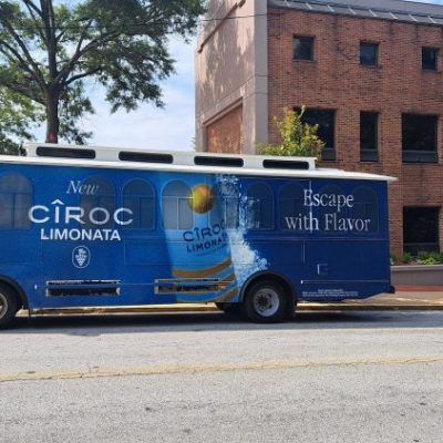 Blue promotional bus for Ciroc Limonata parked on a city street next to a brick building.