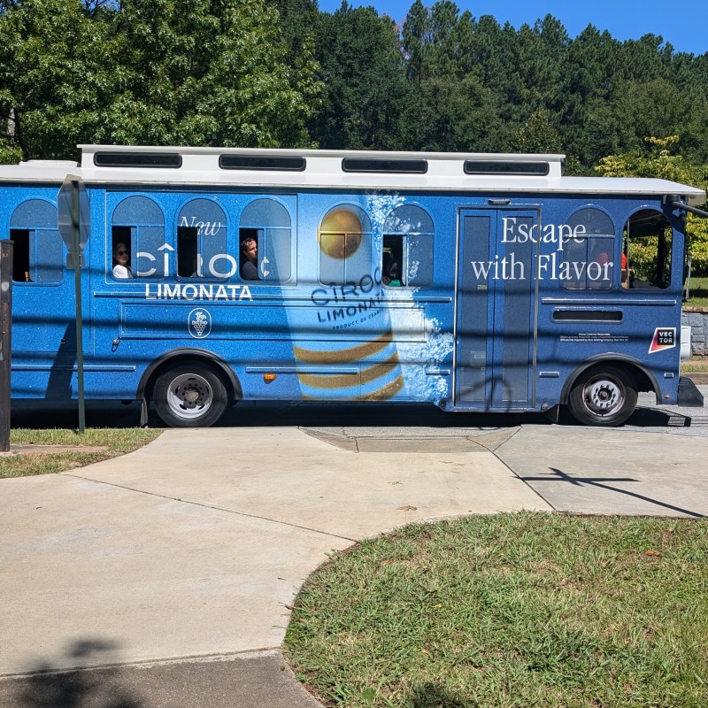 Blue trolley bus with Ciroc Limonata ad parked on a road.