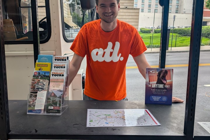 Person in orange shirt stands at tour booth with brochures in Atlanta.